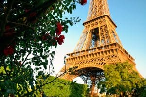 Torre Eiffel vista de baixo com árvores e flores ao redor.